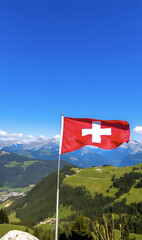 Swiss flag against mountain landscape. Panorama with waving red Swiss flag. Celebration of Swiss National Day. Travel, holiday and tourism concept.