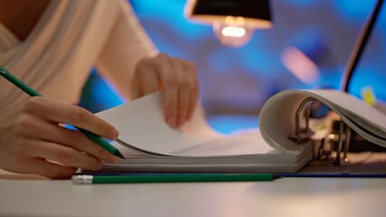 Naklejka premium Workaholic woman sitting at office desk searching through signing overload stack of paper documents in binder folder, close up. Bureaucracy business concept.
