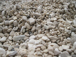 Macro view of gravel beach on the sun. Pebbles on the seaside. Close up of a stone on a sunny summer day.	
