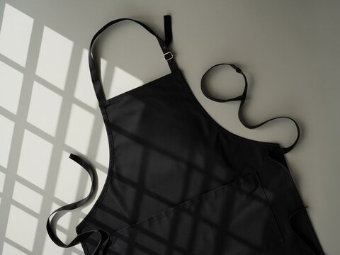 Blank black baker chef apron mockup for professional kitchen staff front view with adjustable ss