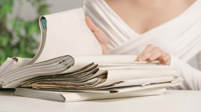 Woman puts on office desk files, sitting and searching through overload stack of folders full of paper documents sheets. Bureaucracy business concept.
