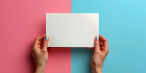 Obraz premium Hand holding a blank white box on colorful paper background during creative workspace setup