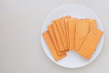 Waffles with chocolate coating. Belgian dessert. Waffles in ceramic plate on a beige background. Top view.