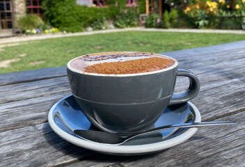 A cup of coffee on the wooden table in the beautiful garden 
