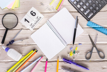 December calendar with number  16. Copy of space note. Top view of blank notepad. Space for text in a checkered sheet, stationery background with accessories.