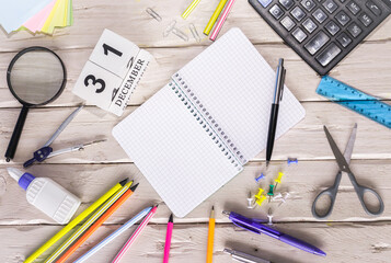 December calendar with number  31. Copy of space note. Top view of blank notepad. Space for text in a checkered sheet, stationery background with accessories.