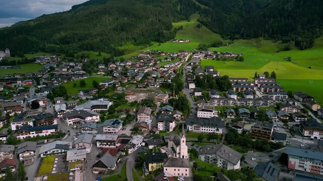 Drone rotating around Kaprun village in Austria, with green mountains and gray roof houses