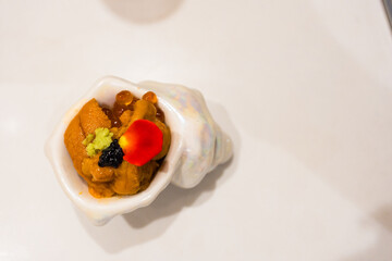 Man hand holding sea urchin in white mini bowl. Top view