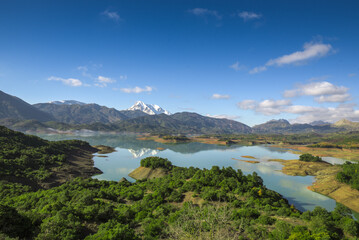 Fototapeta premium Beautiful landscape of lake and reflection of blue sky, clouds and mountains on surface of lake, Panoramic view of lake and snow-covered mountain and Forest trees calm in Jijel Algeria North African.