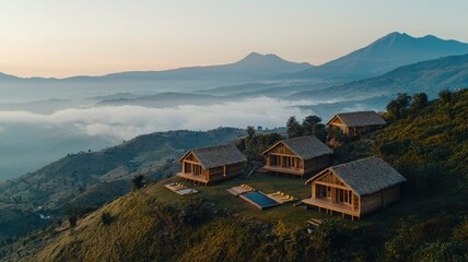 Scenic view of wooden cabins on a hillside with mountains in the background.