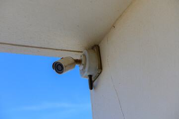 A Surveillance Camera Mounted on a Wall Overlooking a Clear Blue Sky, Capturing Moments in an Outdoor Setting With a Hint of Tranquility