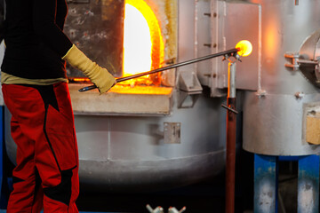 Close-up glassblowing process tube tool with molten glass shaped inside refractory furnace in...