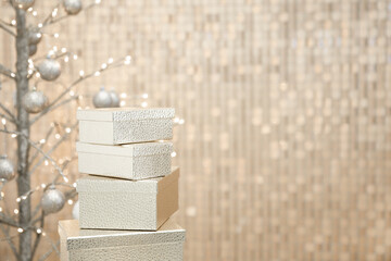 New Year interior decor made of golden boxes, Christmas tree with golden balls against golden wall.