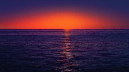 Obraz premium A sea horizon with the sun just dipping below, casting vibrant orange and purple hues across the water.