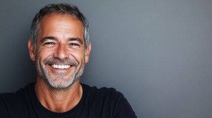 Fototapeta premium A middle-aged man with graying hair and a beard smiles brightly at the camera.