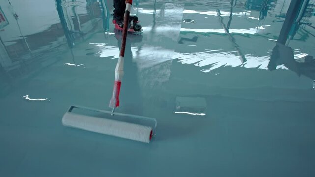Construction worker applying epoxy flooring