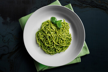 White bowl with portion of trenette with Genoese pesto and basil