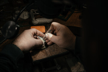 Close-up of a hand of a goldsmith who builds a precious jewel with valuable diamonds. To make the...
