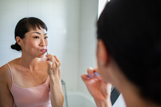 Asian woman brushing teeth in the bathroom - Powered by Adobe