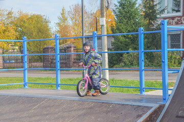 a child, a boy riding a running bike, a bicycle on a sports field, a photo without filters