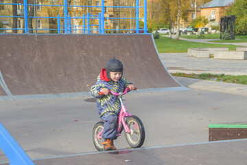 a child, a boy riding a running bike, a bicycle on a sports field, a photo without filters