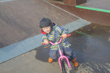 a child, a boy riding a running bike, a bicycle on a sports field, a photo without filters