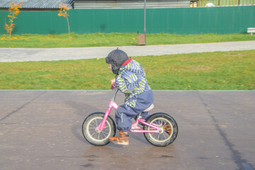 a child, a boy riding a running bike, a bicycle on a sports field, a photo without filters