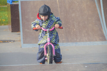 a child, a boy riding a running bike, a bicycle on a sports field, a photo without filters