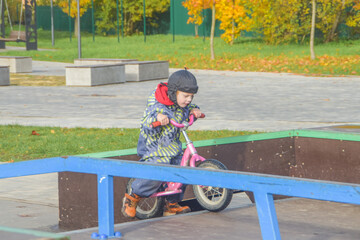 a child, a boy riding a running bike, a bicycle on a sports field, a photo without filters