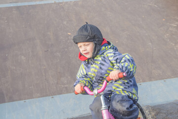 a child, a boy riding a running bike, a bicycle on a sports field, a photo without filters