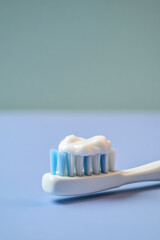 Toothbrush with toothpaste against solid color minimalist background with copy space