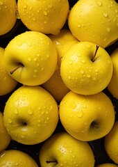 Freshly washed yellow apples arranged closely, showcasing their shiny surfaces and water droplets