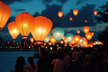 Crowd walking on riverbank at night releasing floating lanterns