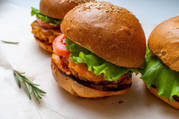 Homemade burgers with beef, tomatoes, onions and salad on a white table