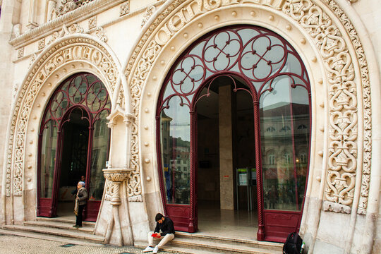 the grand entrance of the Rossio Train Station in Lisbon, Portugal. The intricate Neo-Manueline style architecture is prominently displayed, characterized by lavish stone carvings, ornate details, and