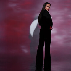 beautiful fashion girl posing in the studio in a classic black suit illuminated by colored light