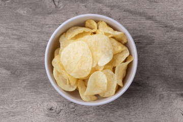 Potato chips in a bowl over wooden table