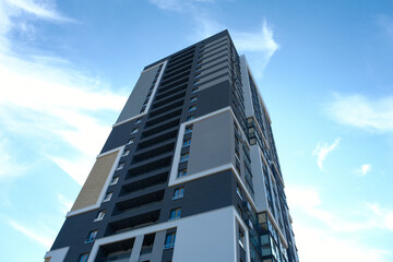 Fototapeta premium Modern residential high-rise building towers against a bright blue sky in a bustling urban area during the day