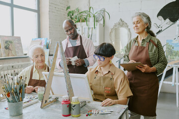 Young professional drawing teacher showing sketch tips for senior students who watching her and...