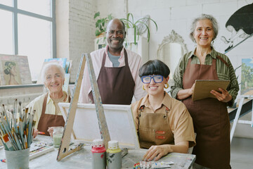 Biracial group of people interested in drawing looking at camera and smiling while having art...
