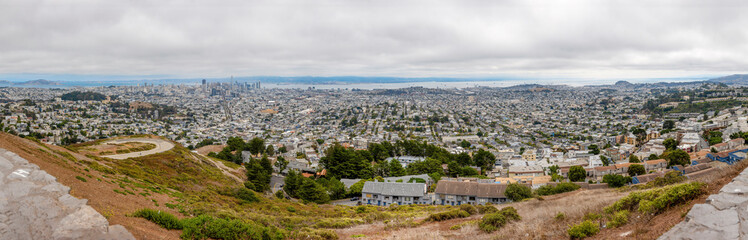 Obraz premium Experience the breathtaking panorama of San Francisco from Twin Peaks, showcasing its iconic skyline and vibrant cityscape under a blanket of mist and clouds.