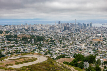 A breathtaking view of San Francisco from Twin Peaks, showcasing its iconic skyline and vibrant cityscape under a blanket of mist and clouds.