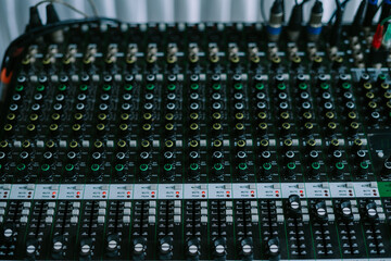 Obraz premium A close-up shot of an audio mixer with various knobs, faders, and buttons