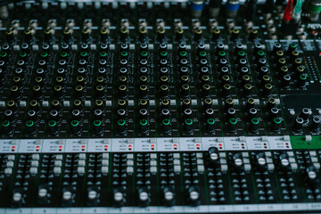 A close-up shot of an audio mixer with various knobs, faders, and buttons