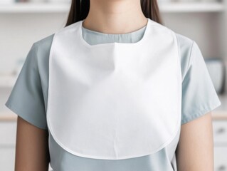 A simple, white bib worn by a person, perfect for dining or arts and crafts activities, adding protection and style.