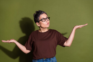 Photo of attractive retired woman compare hold skeptical look empty space dressed stylish brown...