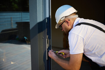 Construction worker installing door in a new house construction site. Man in working attire install...