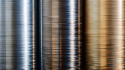 Stacked metal coils in silver, bronze, and gold with brushed texture.