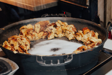 Open kitchen of restaurant or cafe in Vienna, Europe. Big black frying pan with traditional Viennese Kaiserschmarrn. Preparation of shredded sweet pancakes. View through the window from the street