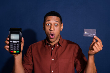 Photo of excited positive guy dressed brown shirt showing bank card terminal isolated blue color background